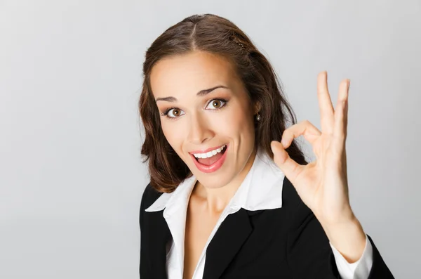 Счастливая деловая женщина с хорошим жестом, над серым — стоковое фото