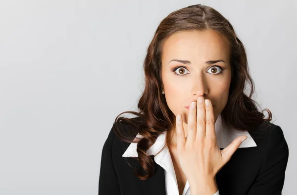 Business woman covering with hands her mouth, over grey — Stock Photo, Image