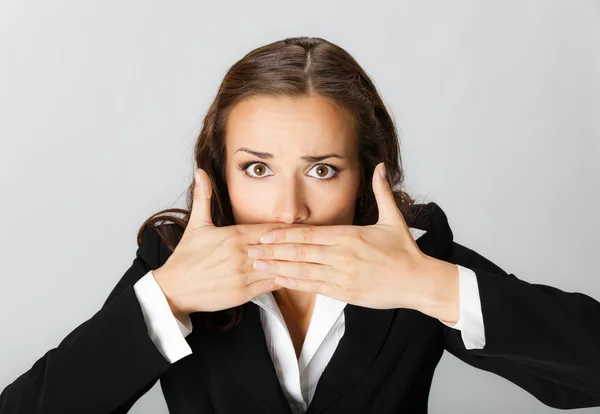 Geschäftsfrau bedeckt mit Händen ihren Mund, über grau — Stockfoto