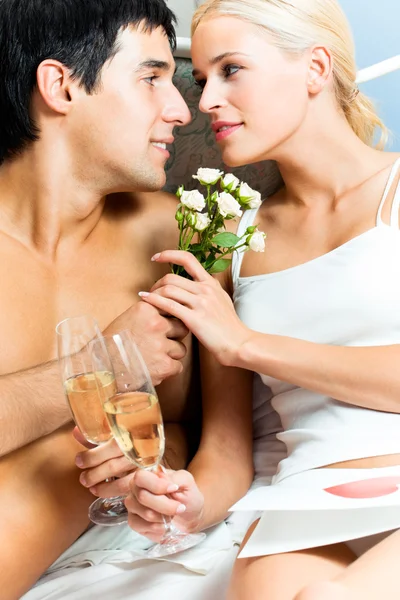 Unga lyckliga amorösa par med champagne på sovrum — Stockfoto