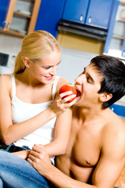 Jovem casal feliz brincando comer maçã em casa — Fotografia de Stock