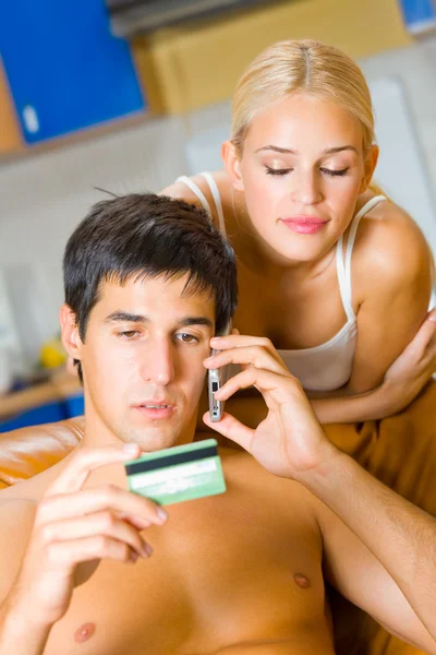 Молодая пара за покупками по мобильному телефону с помощью кредитной карты — стоковое фото