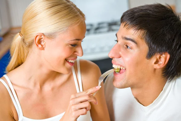 Grappige scène van jonge gelukkige paar speels eten bij keuken — Stockfoto
