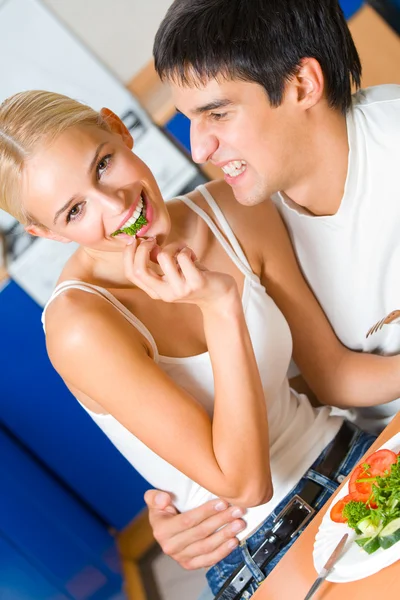 Escena divertida de pareja feliz joven comiendo juguetonamente en la cocina — Foto de Stock