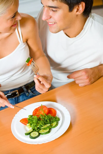 Jovem casal feliz brincando comer, dentro de casa — Fotografia de Stock
