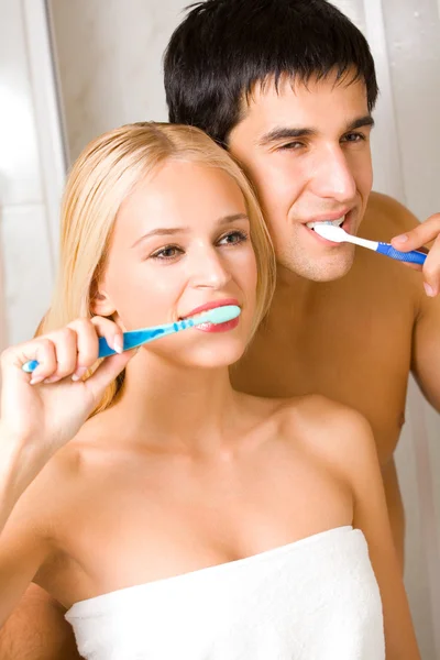 Casal jovem limpando os dentes juntos no banheiro. Foco no homem . — Fotografia de Stock