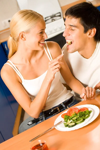 Funny scene of young happy couple playfully eating at kitchen — Stock Photo, Image