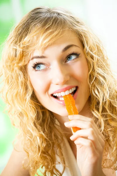 Портрет молодой женщины, поедающей морковь дома — стоковое фото