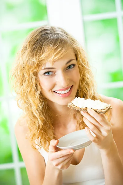 Donna che mangia pane croccante con formaggio a casa — Foto Stock