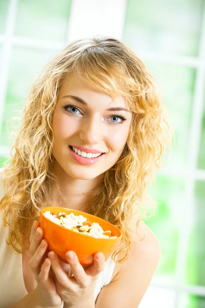 Młoda kobieta uśmiechający się jedzenie muślinu w domu — Zdjęcie stockowe