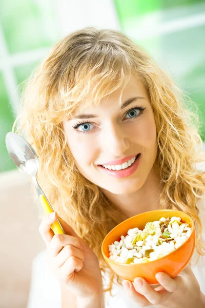 Jovem sorrindo mulher comendo musselina em casa — Fotografia de Stock