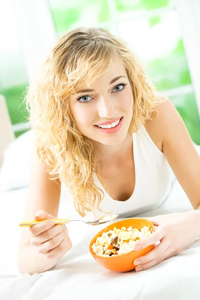 Young smiling woman eating muslin at home — Stock Photo, Image