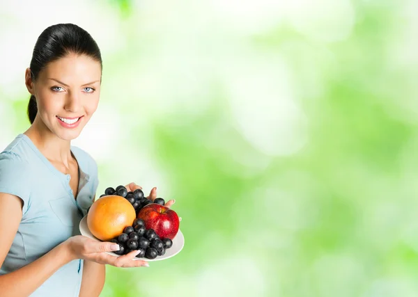 Jeune femme souriante heureuse avec assiette de fruits, en plein air — Photo