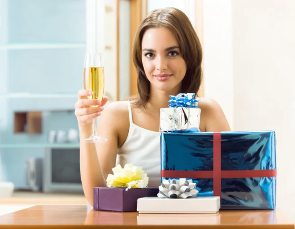Femme avec champagne et des cadeaux à la maison — Photo