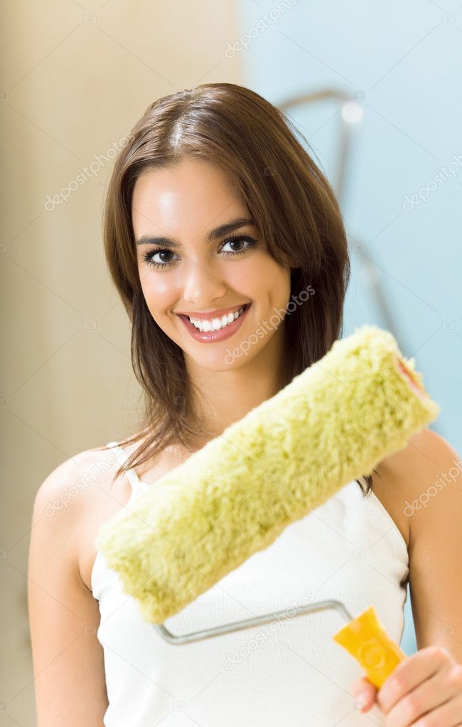 Happy woman with paint roller in new house