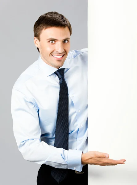 Hombre de negocios mostrando letrero en blanco, sobre gris —  Fotos de Stock