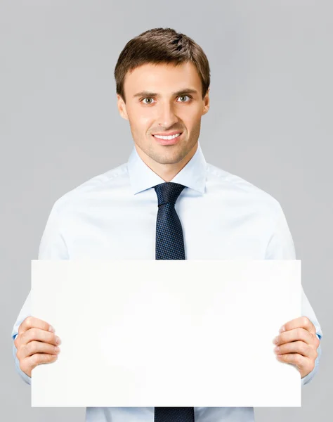 Geschäftsmann zeigt leeres Schild, über grau — Stockfoto