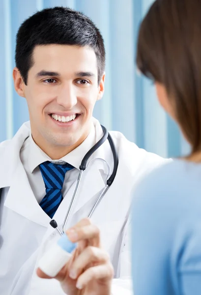 Médico sonriente con medicamento y paciente en el consultorio — Foto de Stock
