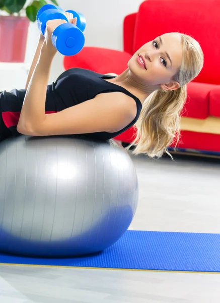 Frau trainiert mit Hantel auf Fitnessball, zu Hause — Stockfoto