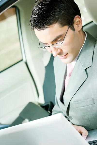 Affärsman som arbetar med laptop i bilen — Stockfoto
