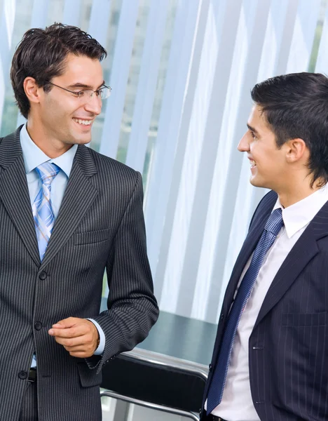 Два счастливых успешных бизнесмена разговаривают в офисе — стоковое фото