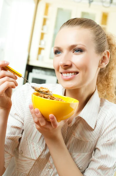 Joven mujer sonriente comiendo muselina en casa — Foto de Stock