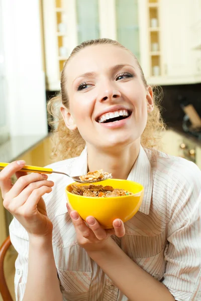 Молодая улыбающаяся женщина ест муслин дома — стоковое фото