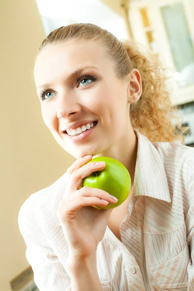 Молода щаслива усміхнена жінка з яблуком, вдома — стокове фото