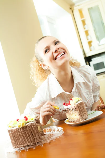 Young happy smiling beautiful young woman eating torte at home — Stock Photo, Image
