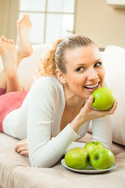 Молодая счастливая улыбающаяся женщина с яблоками, дома — стоковое фото
