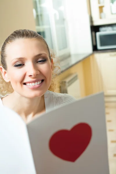 Unga glada leende kvinna, läsa alla hjärtans-kort hemma — Stockfoto