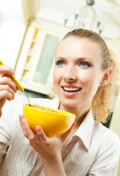 Молодая улыбающаяся женщина ест муслин дома — стоковое фото