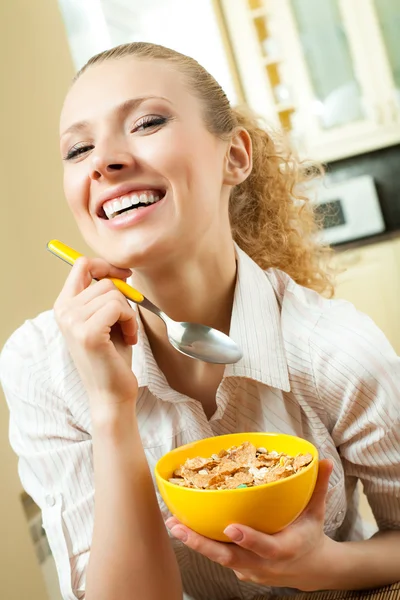 Joven mujer sonriente comiendo muselina en casa —  Fotos de Stock
