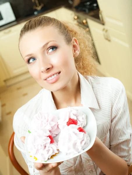 Retrato de jovem feliz bonita sorrindo mulher loira comendo bolos em casa — Fotografia de Stock