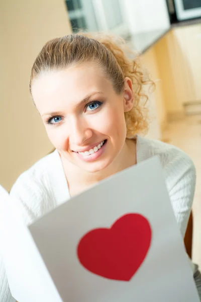Young happy smiling woman, reading valentine card at home — Stock Photo, Image