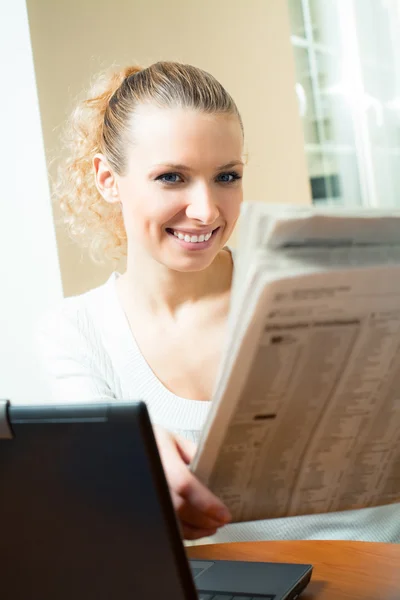 Młody szczęśliwy uśmiechający się piękna młoda kobieta czytanie gazety w domu — Zdjęcie stockowe