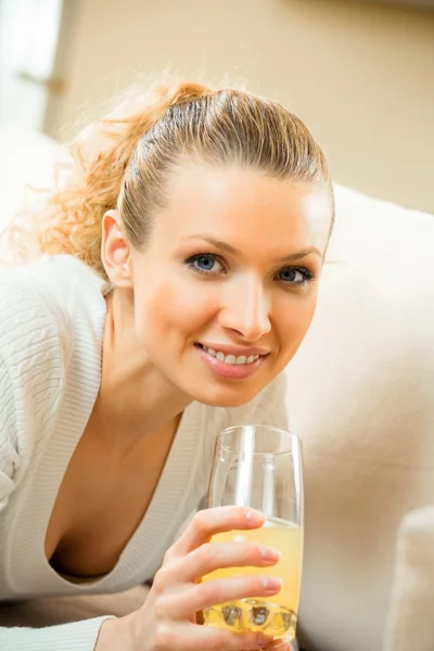 Junge glücklich lächelnde Frau trinkt zu Hause Orangensaft — Stockfoto