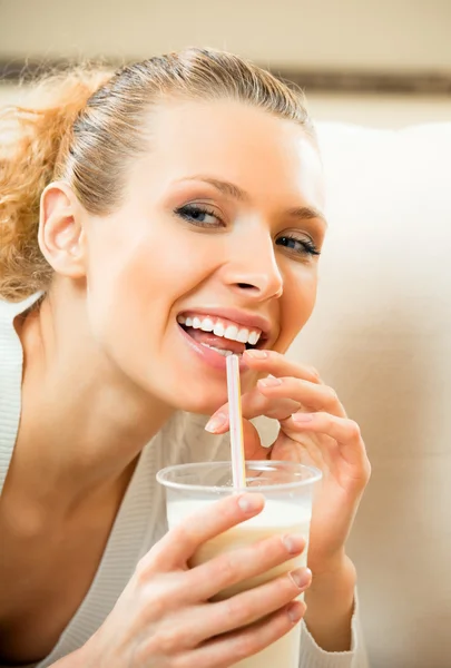 Молода щаслива усміхнена жінка п'є молоко вдома — стокове фото