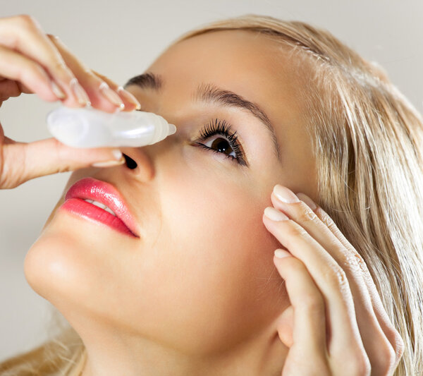 Young woman dripping eyes at home