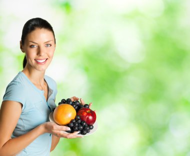 Woman with plate of fruits, outdoors clipart