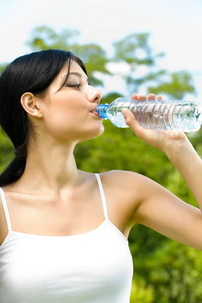 Женщина пьет воду на тренировке, на открытом воздухе — стоковое фото