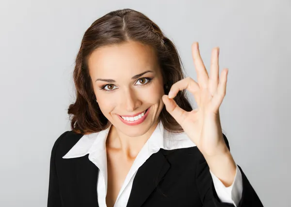 Gelukkig zakenvrouw met oke gebaar, over grijs — Stockfoto