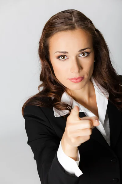 Серйозна бізнес-леді вказує пальцем на глядача, над сірим — стокове фото