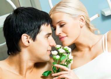 Happy couple with flowers at home clipart