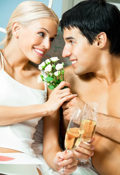 Casal com champanhe e flores no quarto — Fotografia de Stock