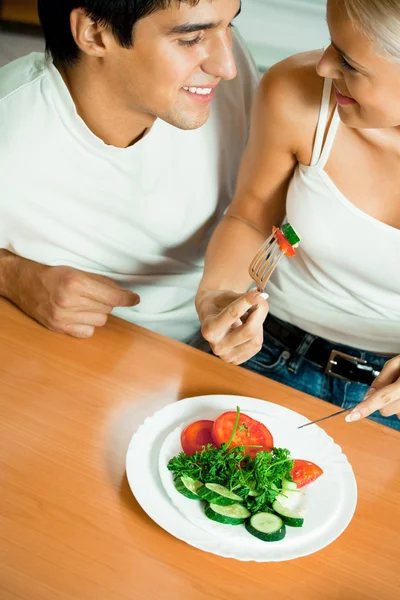 Молодая счастливая пара ест салат — стоковое фото
