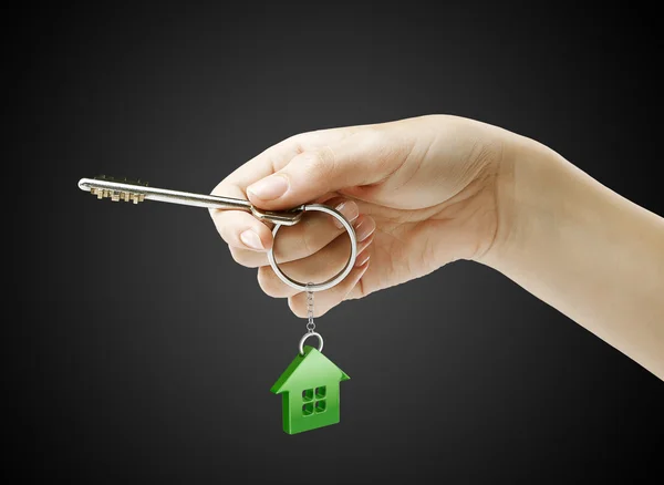 Hand holding key with a keychain in the shape of the house — Stock Photo, Image