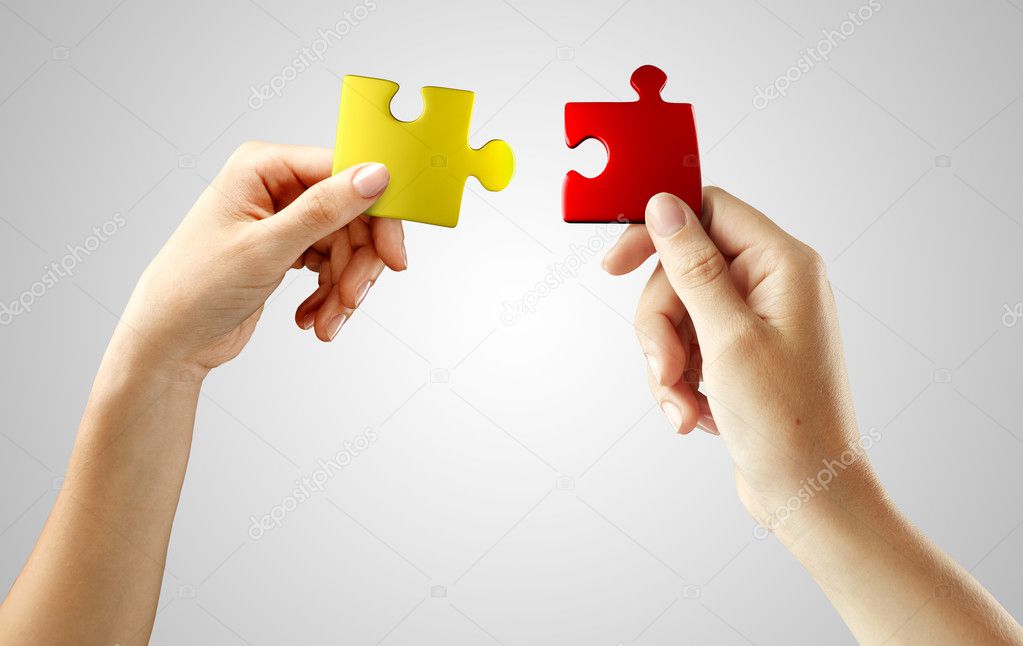Hands with puzzle on gray background.