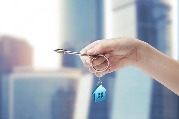 Hand ingedrukt met een sleutelhanger in de vorm van het huis. — Stockfoto