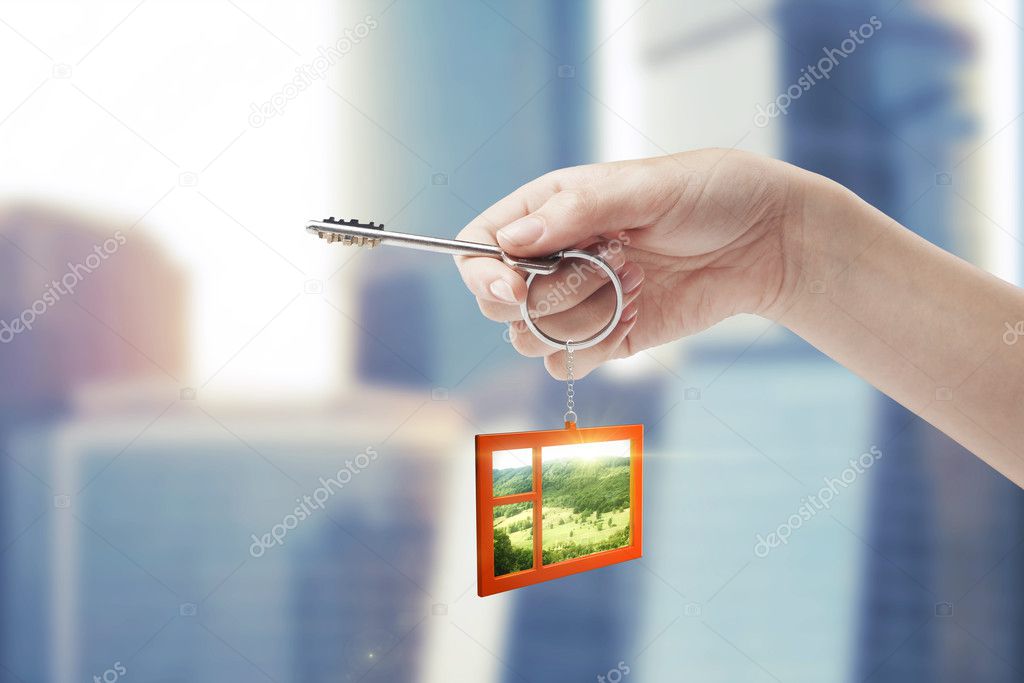 Hand holding key with a keychain in the shape of the window